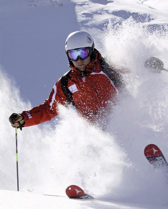 Skischulwesen Heute Skifahrer mit rotem Skianzug im Puderschnee